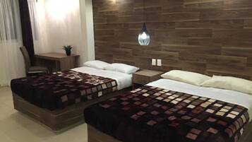 A hotel room with two beds, a desk, and a chair.