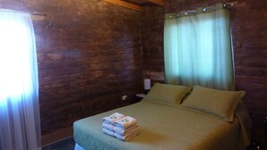 Une chambre avec un lit, une table de chevet, une lampe et une fenêtre avec des rideaux.