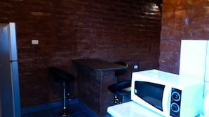 Une cuisine équipée d’un four à micro-ondes, de deux tabourets de bar et d’un réfrigérateur.