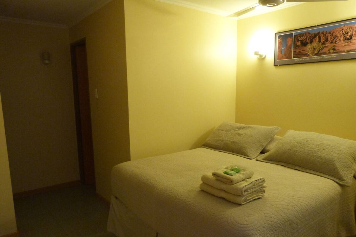 A hotel room with a bed, pillows, and a folded towel on the bed.