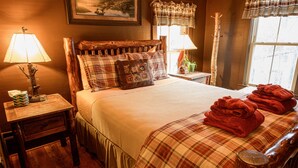 A cozy bedroom with a wooden headboard, a plaid bedspread, and a stack of red towels on the bed.