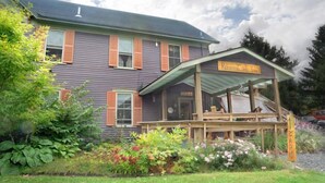 A two-story building with a porch and a sign that reads "Rocker Lodge Inn." - RoosterComb Inn (Keene Valley)