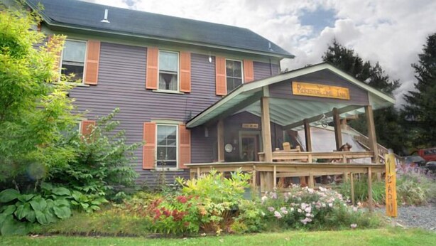 A two-story building with a porch and a sign that reads "Rocker Lodge Inn."