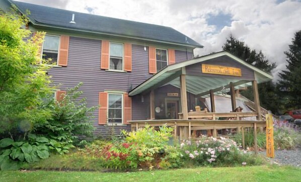 A two-story building with a porch and a sign that reads "Rocker Lodge Inn."