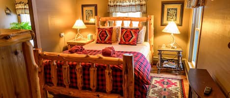 Un dormitorio acogedor con una cama de madera, dos mesitas de noche con lámparas, una alfombra estampada y un banco de madera.