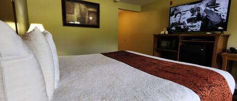 A hotel room with a large bed, a television, and a microwave.