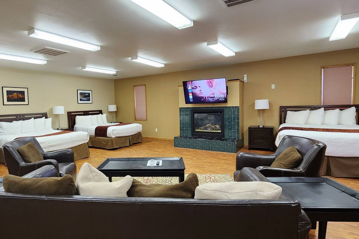 A hotel room with two beds, a sofa, a TV, and a fireplace.