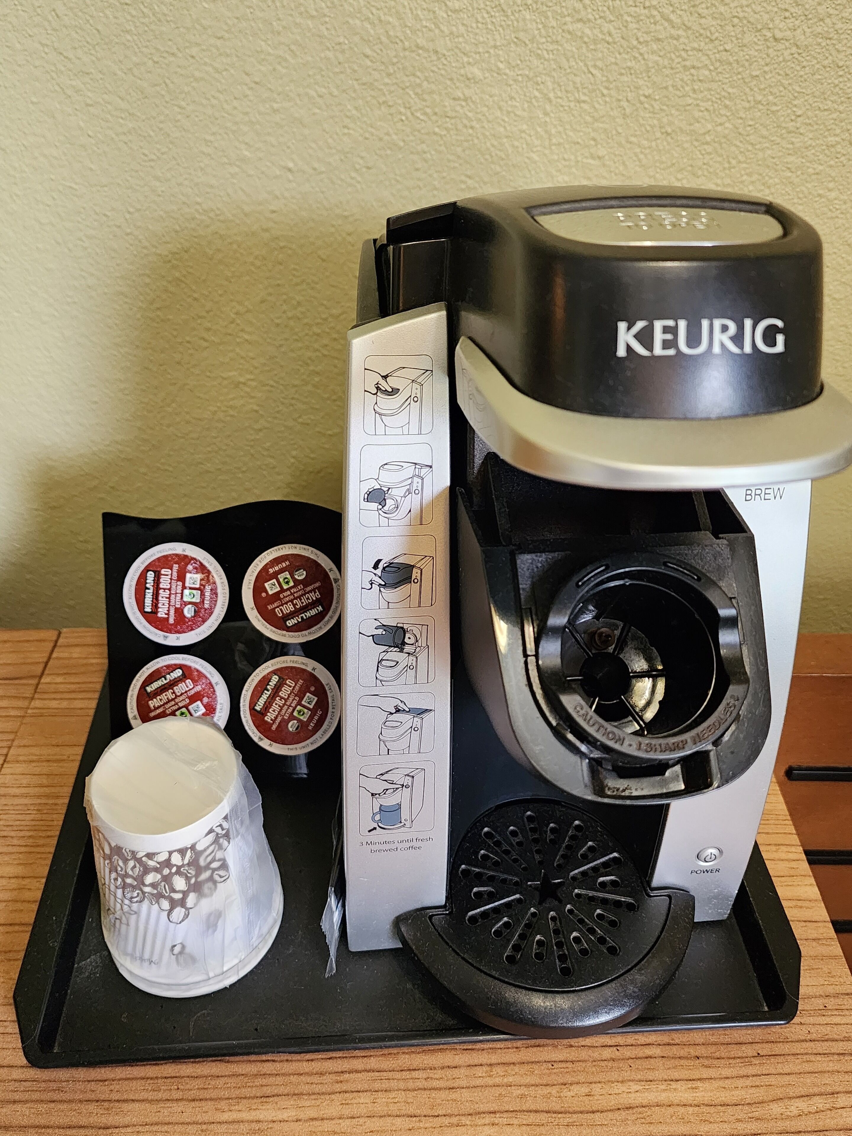 Una cafetera Keurig con cuatro cápsulas Keurig K-Cups sobre una bandeja negra.
