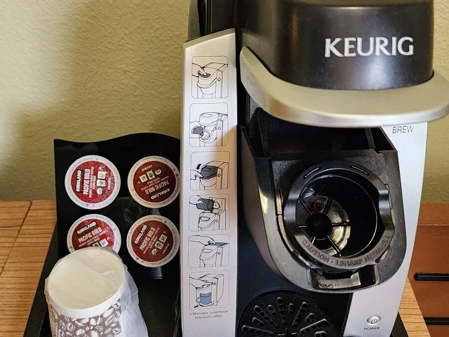 A Keurig coffee maker with four Keurig K-Cups on a black tray.