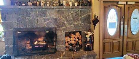 A stone fireplace with a fire, a mantel with decorative items, and a door with a frosted glass window.