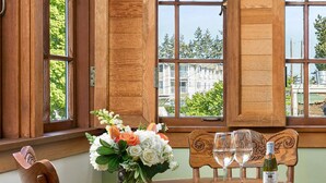 A wooden dining table with a vase of flowers, two wine glasses, and a bottle of wine. - The La Conner Inn (La Conner)