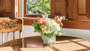 A round wooden table with a clear glass vase containing a bouquet of flowers. - The La Conner Inn (La Conner)