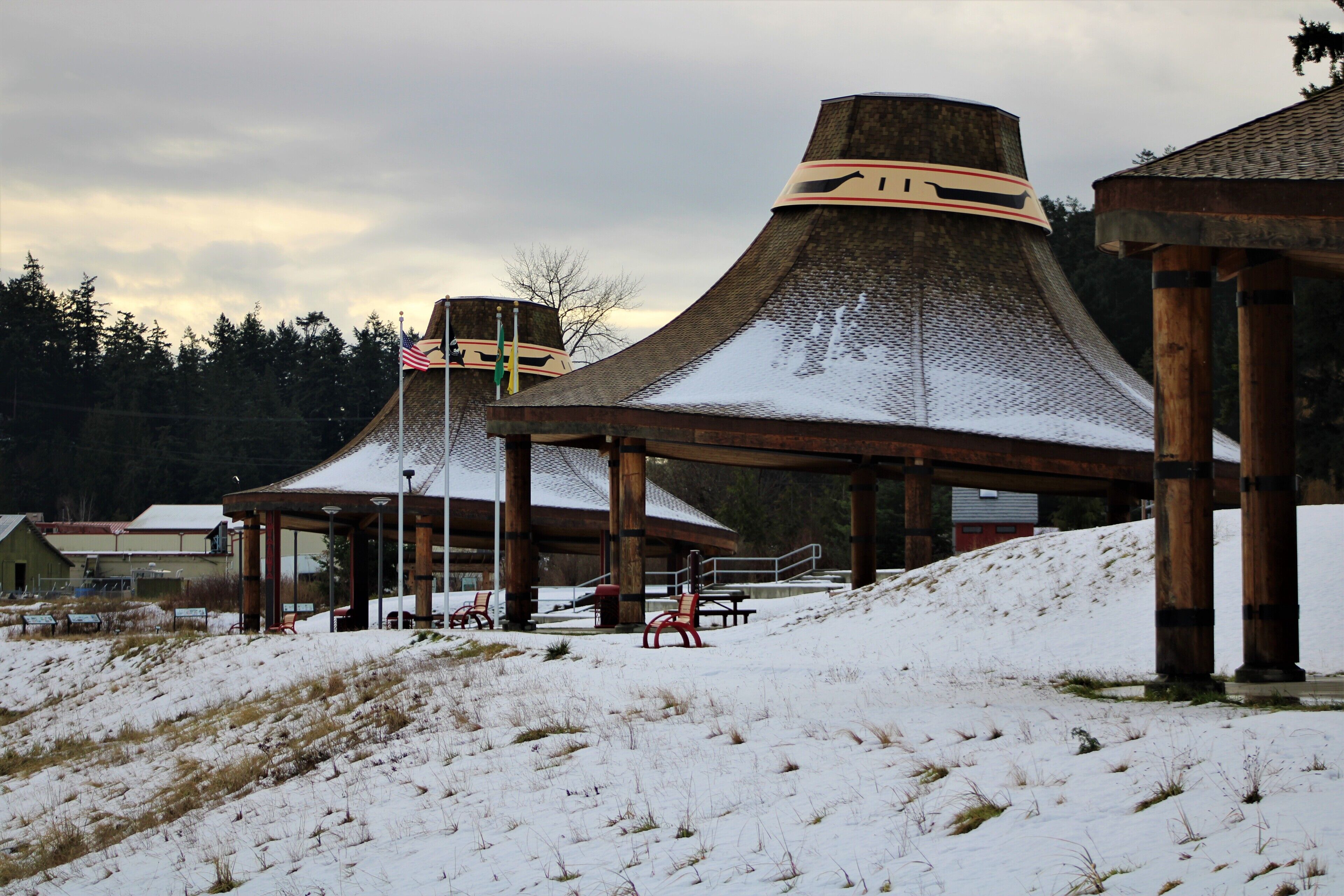 Un edificio cubierto de nieve con un diseño arquitectónico único, que presenta una estructura central grande y anexos más pequeños.