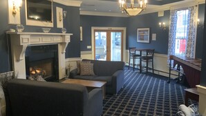 Un salon avec une cheminée, un canapé, une table basse et un tapis à motifs.