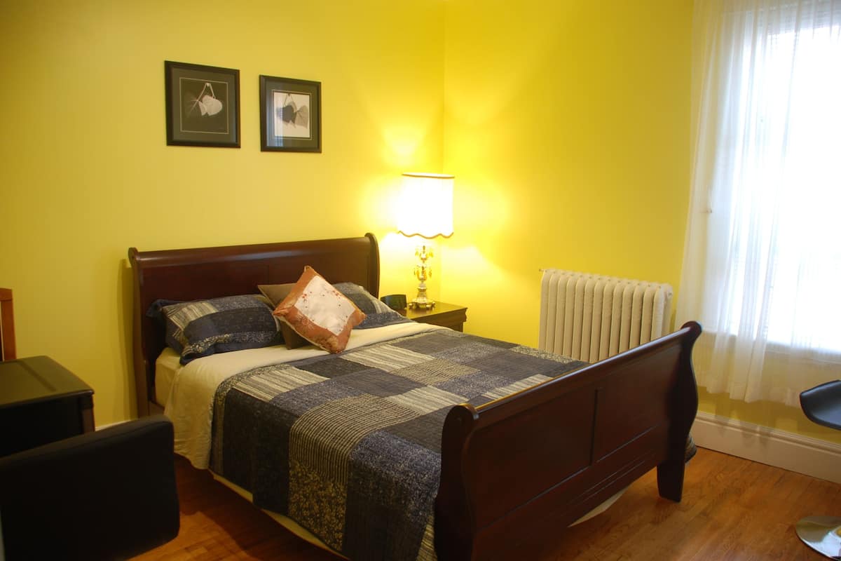 A bedroom with a wooden bed, a bedside lamp, and two framed pictures on the wall.