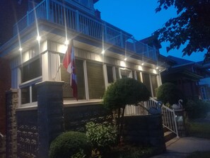 A two-story house with a balcony, a flag, and a well-maintained garden. - Ambassador B&B Guest Home (Stratford)
