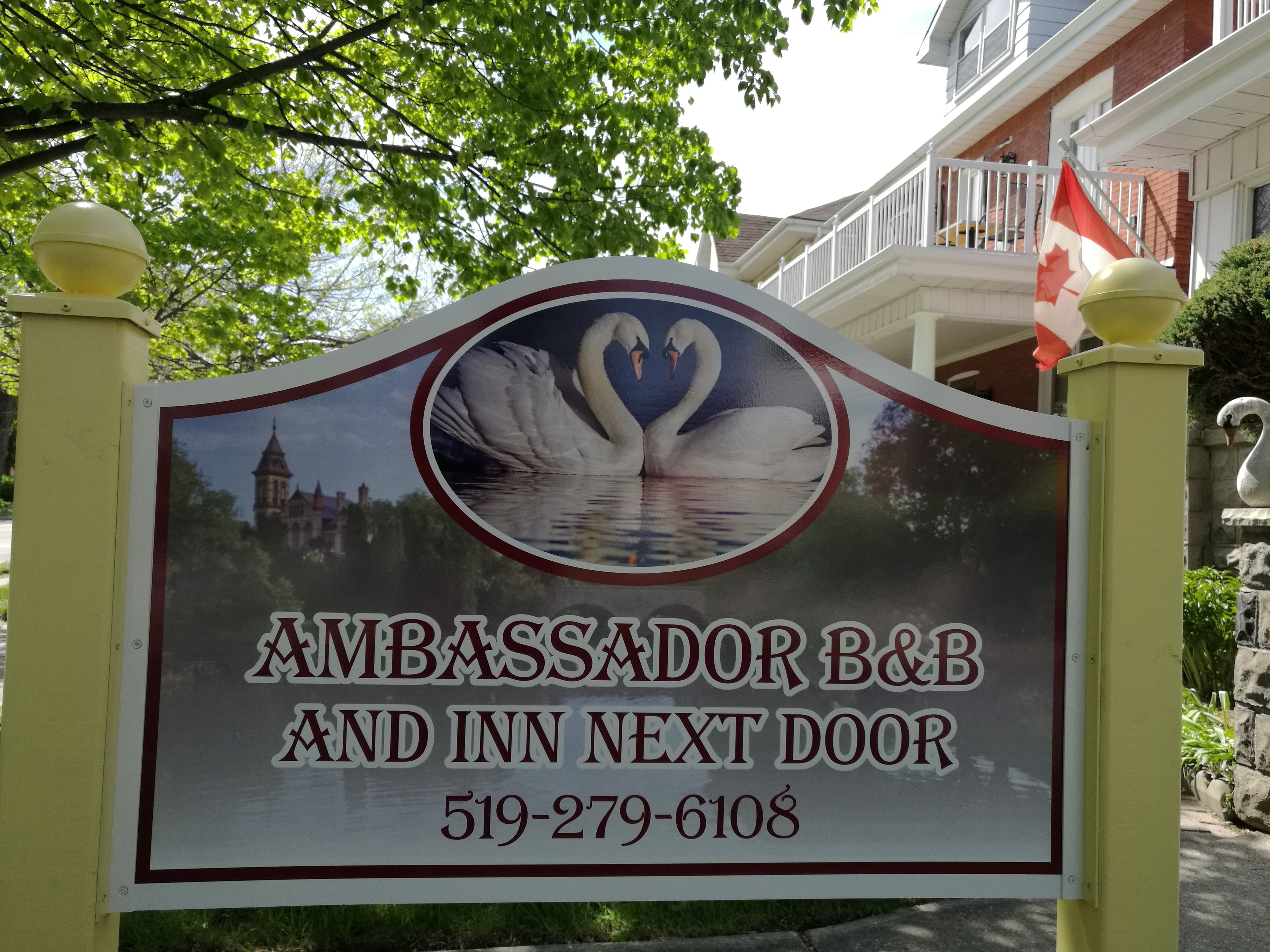 A sign for Ambassador B&B and Inn Next Door with a swan image and contact number.