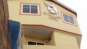 The exterior of the Avellan Hotel with a clear view of the entrance, a water feature, and the hotel's logo. - Hotel Avellán (Manta)