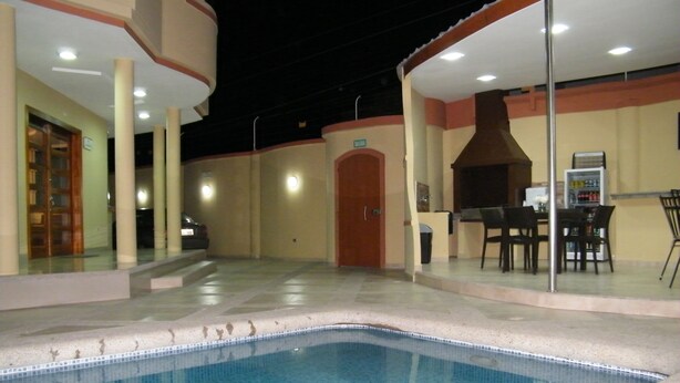An indoor swimming pool with tiled flooring, a covered seating area with tables and chairs, and a door marked "SAUNA". - Hotel Avellán (Manta)