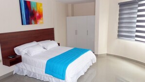 A hotel room with a large bed, a nightstand, a wardrobe, and a window with blinds. - Hotel Avellán (Manta)
