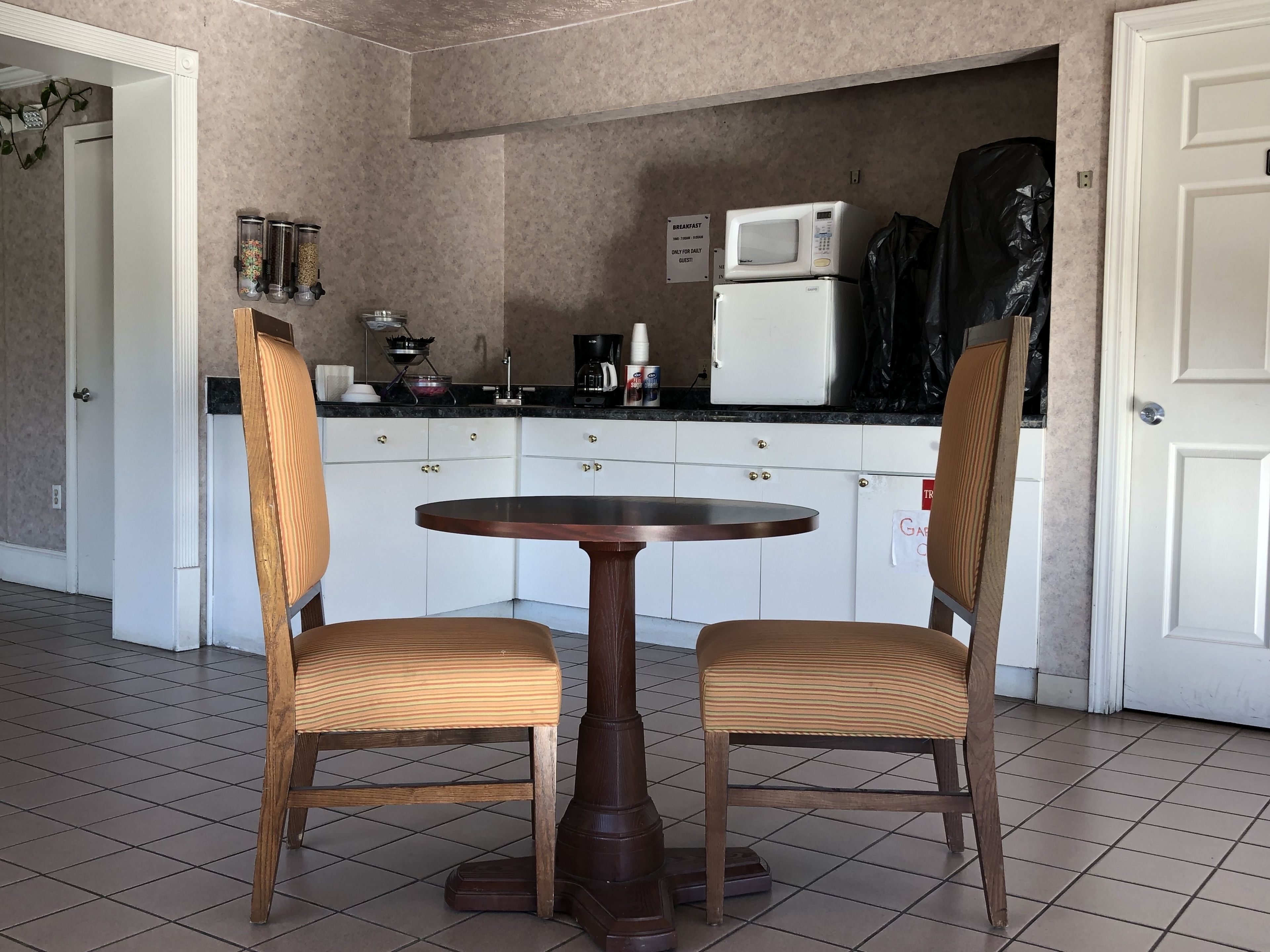 A small kitchen with a round table and two chairs, a microwave, and a coffee maker.