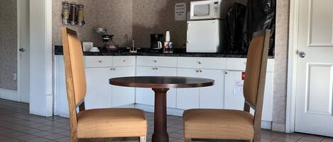 A small kitchen with a round table and two chairs, a microwave, and a coffee maker.