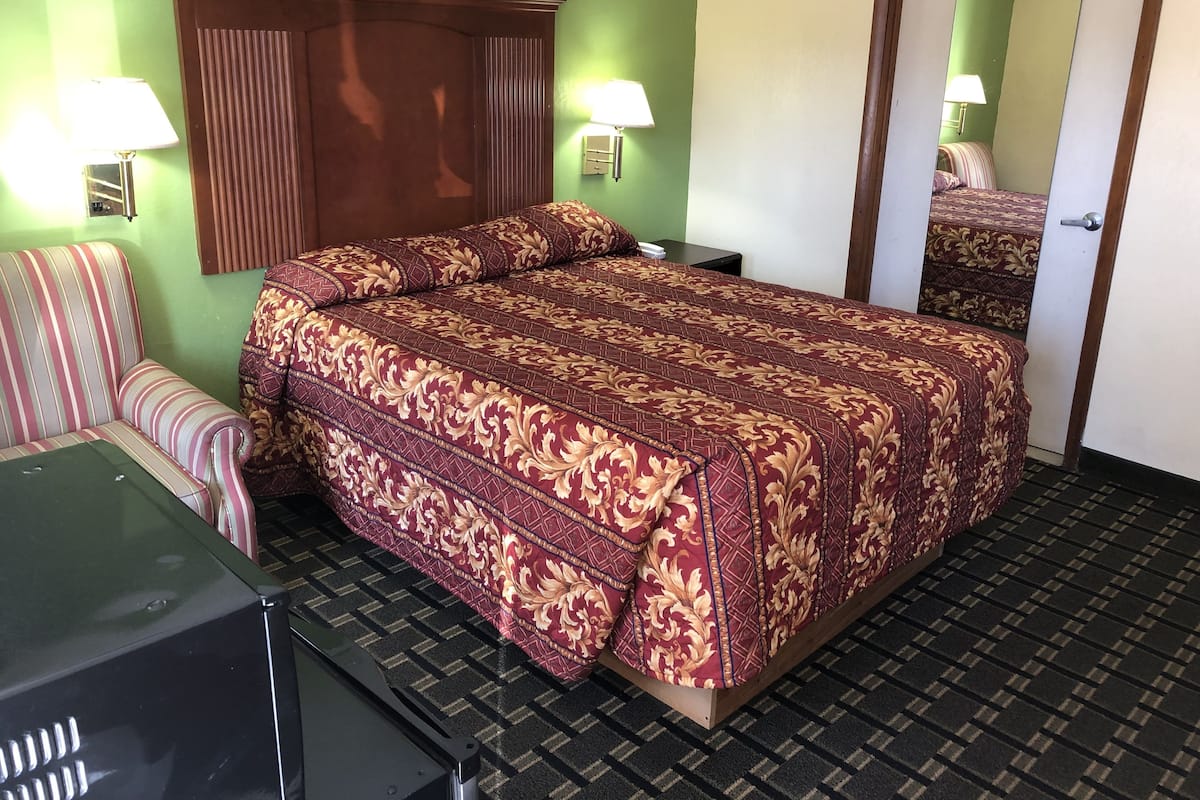 Ett hotellrum med en stor säng, en soffa, ett skrivbord och en spegel.