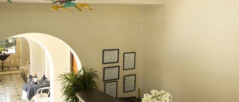 A reception area with a wooden desk, a vase of flowers, and a wall with hanging bird decorations.