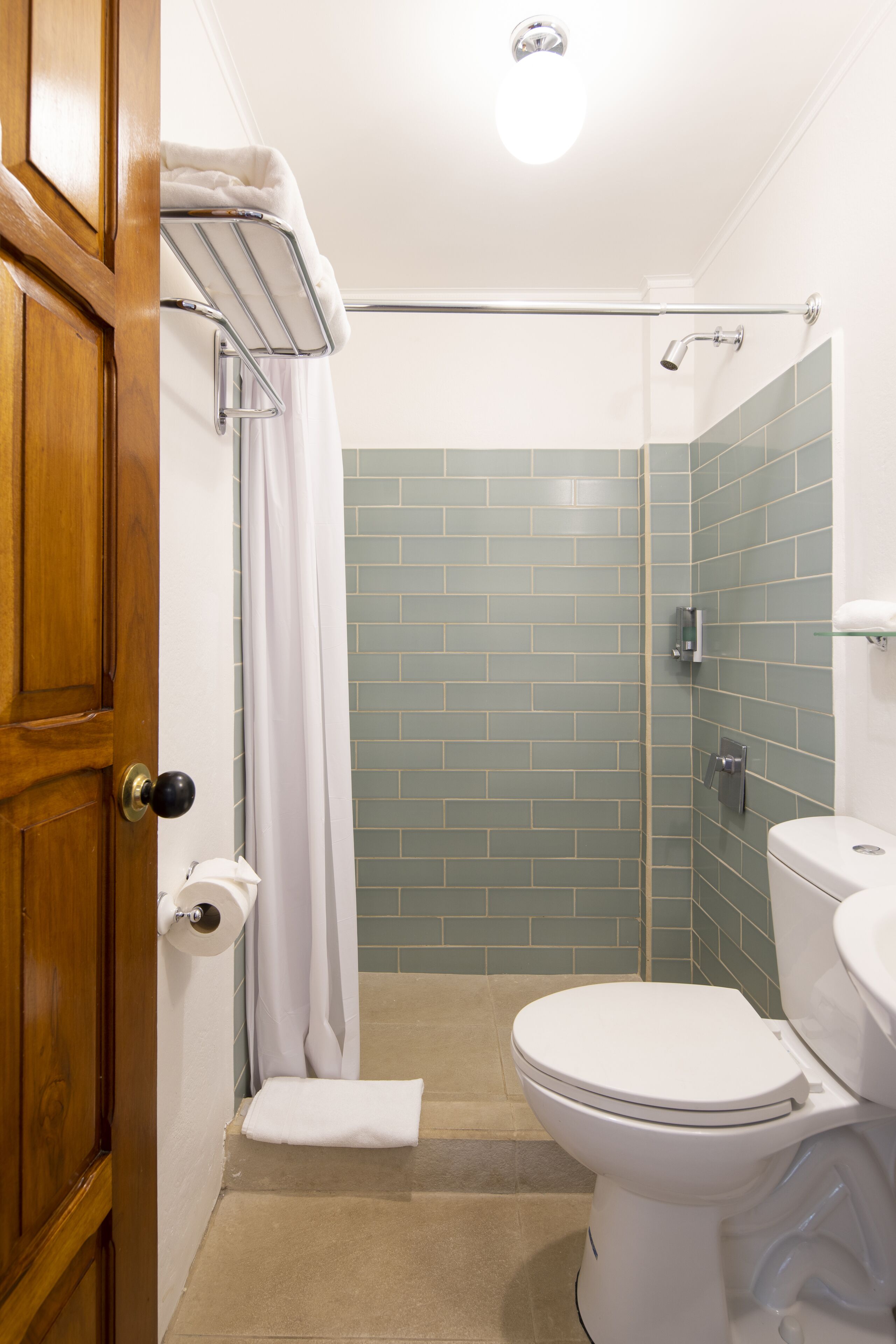 A bathroom with a toilet, a shower with a glass door, and a towel rack.