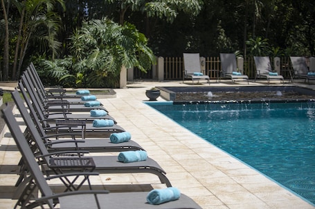 Una piscina al aire libre, sillones reclinables de piscina