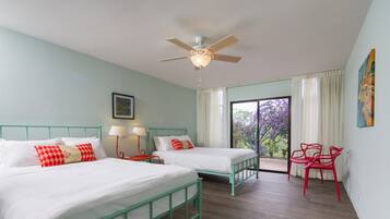 A bedroom with two beds, a ceiling fan, a window with curtains, and a red chair.