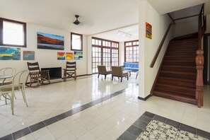 A spacious lobby with a tiled floor, a staircase, and several chairs.