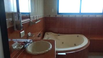 Un bagno con una vasca da bagno ampia, un lavandino e una finestra che lascia entrare luce naturale.