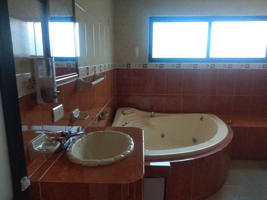 Un bagno con una vasca da bagno ampia, un lavandino e una finestra che lascia entrare luce naturale.