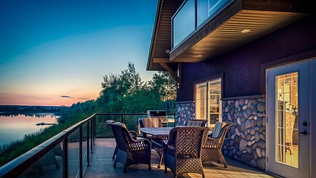 Une terrasse avec des meubles d’extérieur, un barbecue et un mur en pierre.
