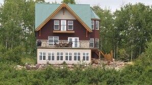 Une maison à deux étages, dotée d’un toit végétalisé, d’un balcon avec une balustrade en pierre et de fondations en pierre.