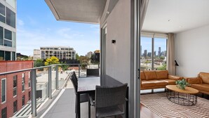 Un balcon avec une table à manger et des chaises, un canapé et une table basse.