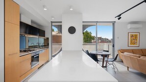 Une cuisine moderne dotée d’un îlot central, un coin repas avec une table ronde et des chaises, et un espace salon avec un canapé.