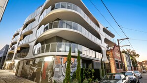 Un immeuble moderne à plusieurs étages, doté de balcons, de grandes fenêtres et d’un mur recouvert de graffitis.