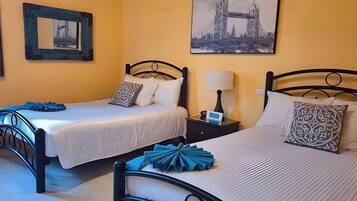 Una habitación de hotel con dos camas, una mesita de noche, una lámpara y un cuadro con una imagen de un puente en la pared.