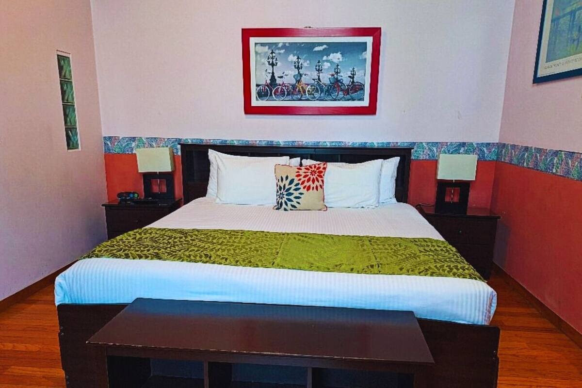 A bed with a green and white bedspread, two bedside tables, and a wall-mounted picture.