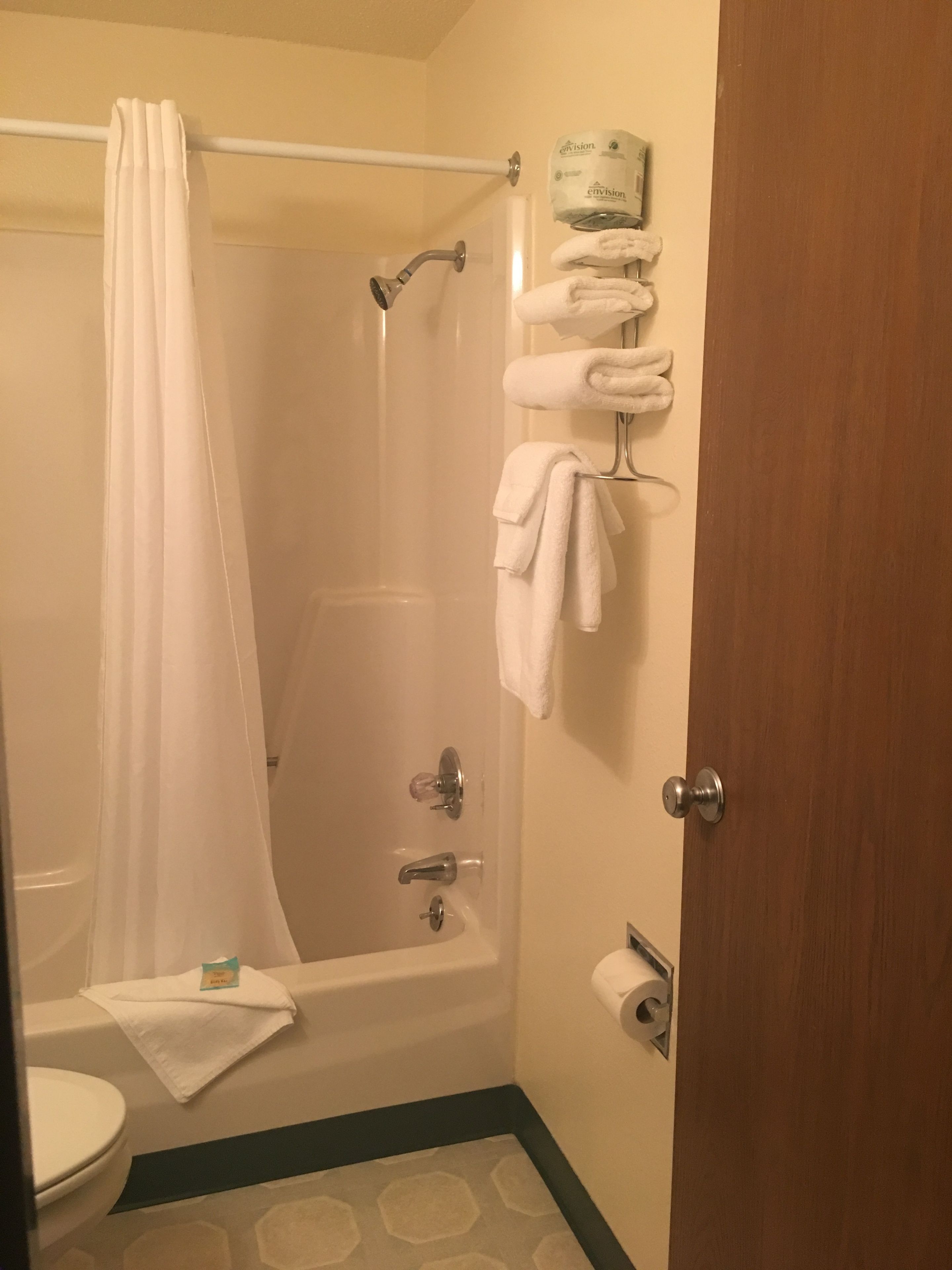 Ein Badezimmer mit Dusche, Toilette und einem Handtuchhalter mit Handtüchern.