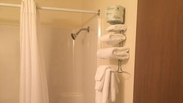Ein Badezimmer mit Dusche, Toilette und einem Handtuchhalter mit Handtüchern.