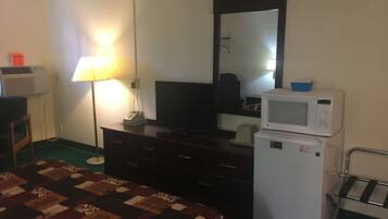 A hotel room with a bed, dresser, television, microwave, and a mirror.