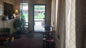 A restaurant interior with a patterned carpet, wooden chairs, a chandelier, and deer antlers on the wall. - Mobridge Kountry Inn (Mobridge)