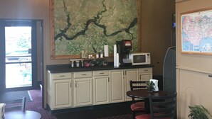 A restaurant with a large map on the wall, a dining area with tables and chairs, a kitchen area with a microwave, and a chandelier with multiple light bulbs. - Mobridge Kountry Inn (Mobridge)