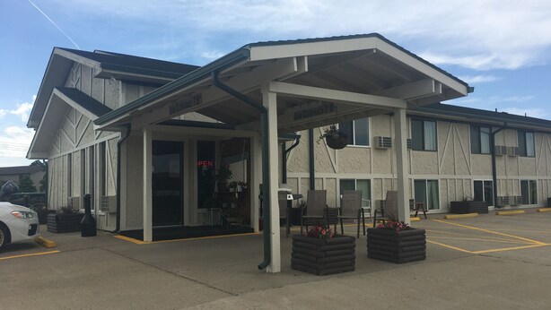 A hotel with a covered entrance, outdoor seating, and a clear sky. - Mobridge Kountry Inn (Mobridge)
