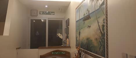 A hallway with a wooden staircase, a painting of a beach scene, and a sign that reads "Jeffrey S."