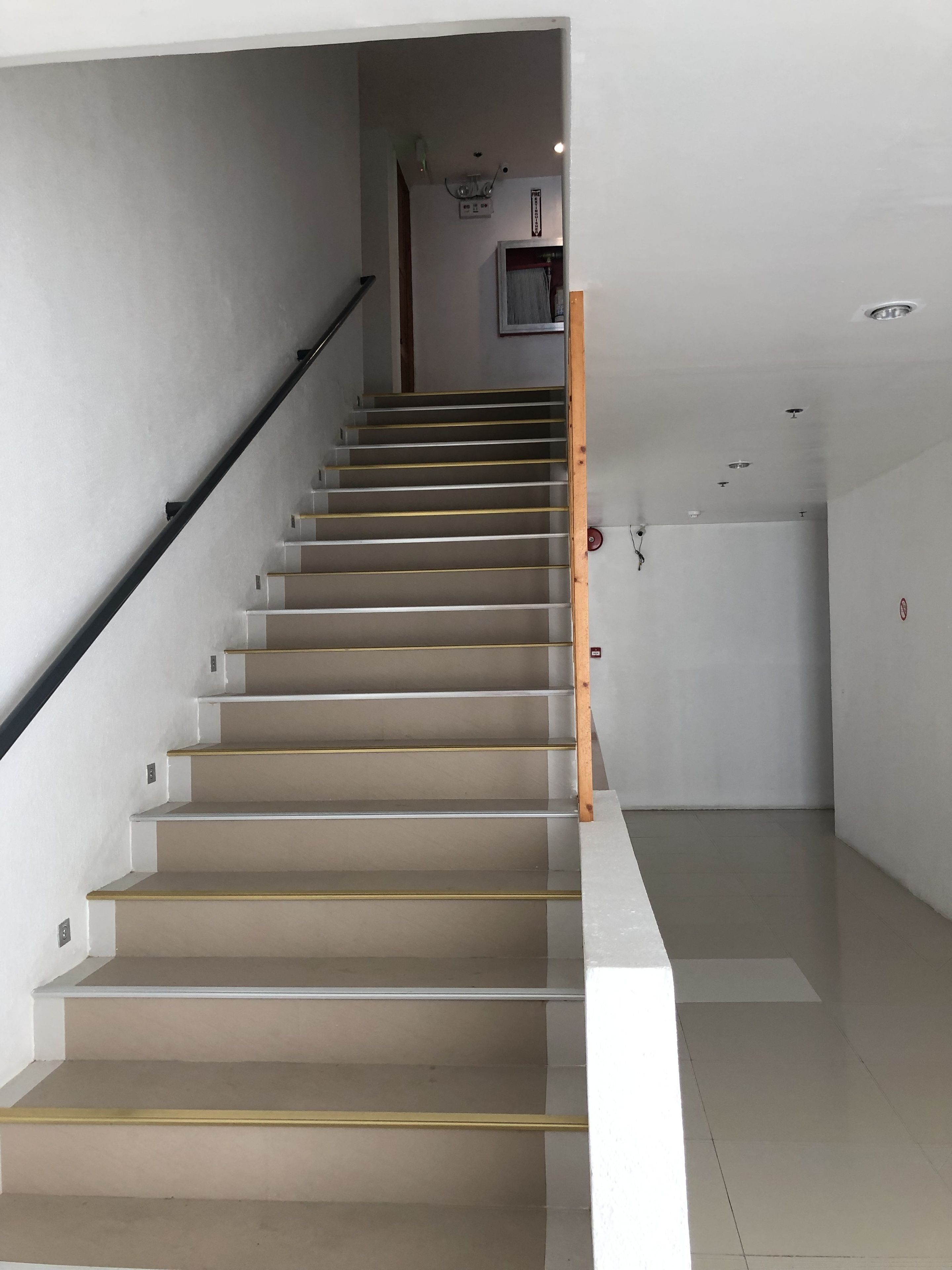 Un escalier avec une rampe en bois et des marches de couleur beige menant à un palier.