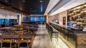 A modern bar area with a long counter, seating, and a brick wall backdrop. - IBC Hotel (Seoul)